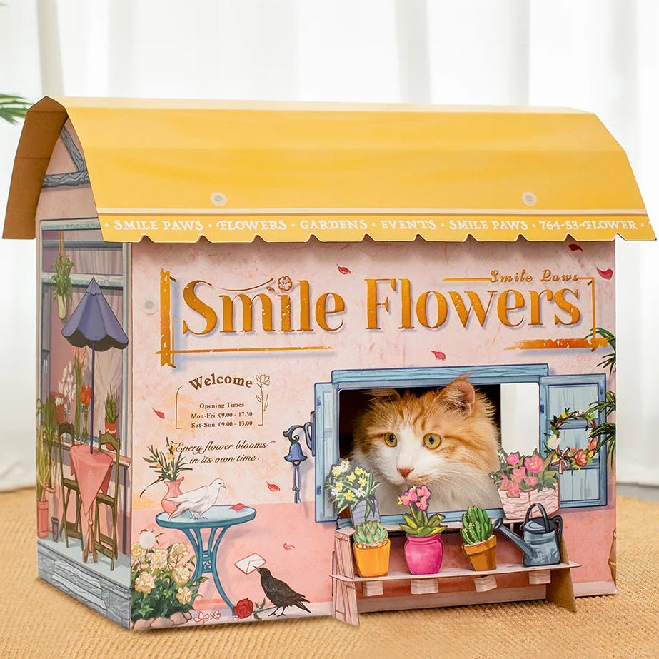 A cardboard flower shop with an orange and white cat inside