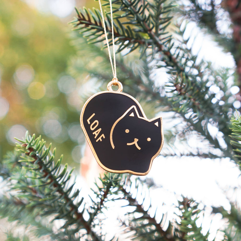 Black cat-shaped ornament with 'LOAF' text hanging on a Christmas tree.
