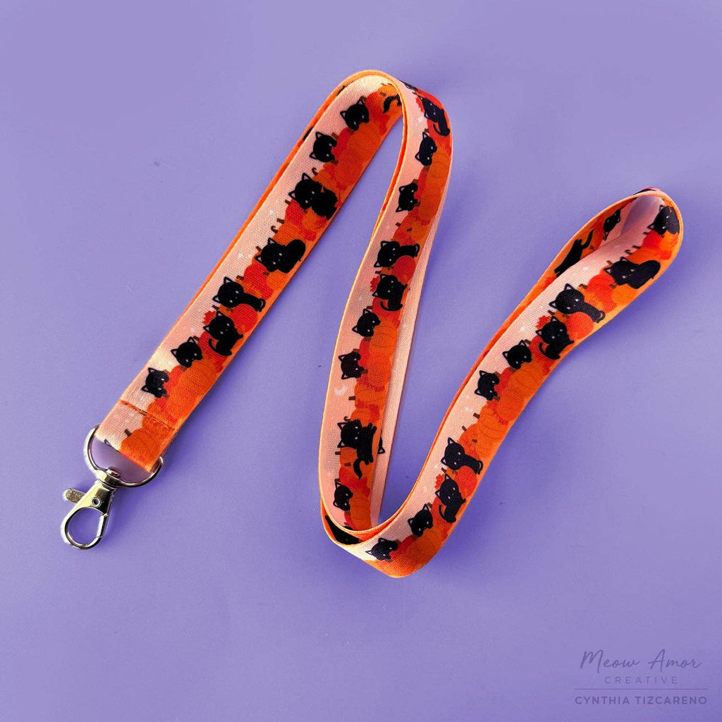 Lanyard with black cat pattern on an orange background against a purple background