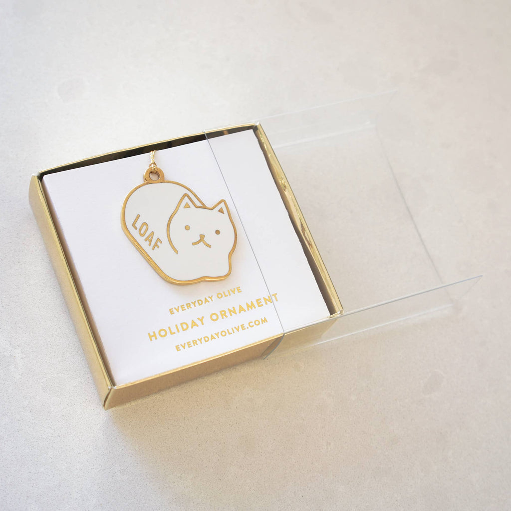 White cat-shaped ornament with 'LOAF' on a white card in a clear box on a light gray background