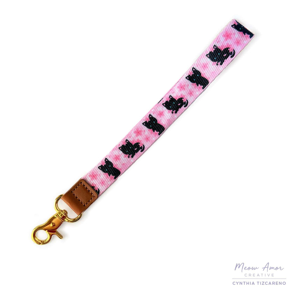 Pink lanyard with black cat pattern and gold clasp on a white background