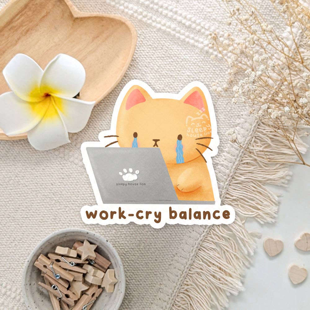 Sticker of a cat holding a laptop with 'work-cry balance' text on a decorative background.