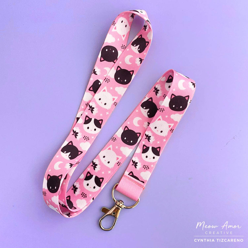 Pink lanyard with black and white cat pattern on a purple background