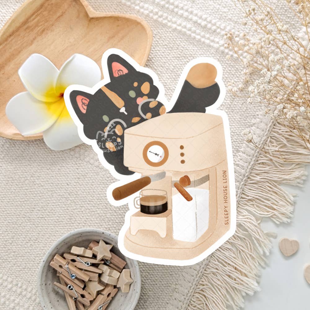Sticker of a cat using an espresso machine on a textured surface with flowers and wooden items.