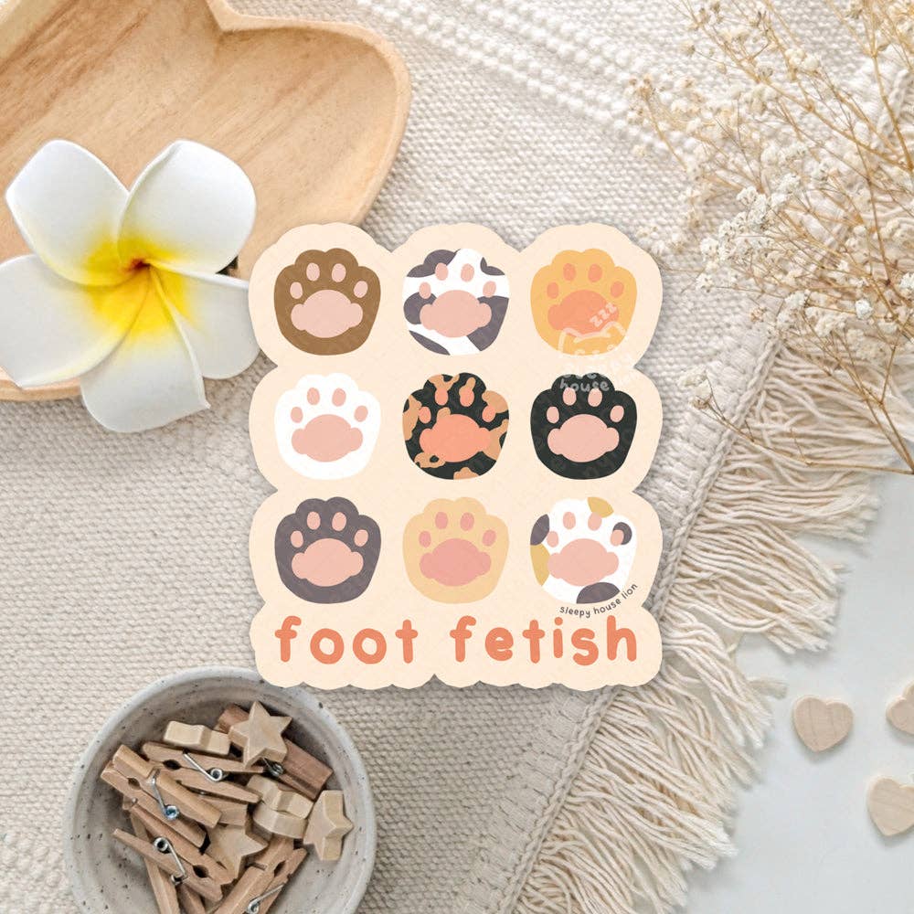 Set of paw print stickers with 'foot fetish' text on a decorative background with flowers and wooden items.