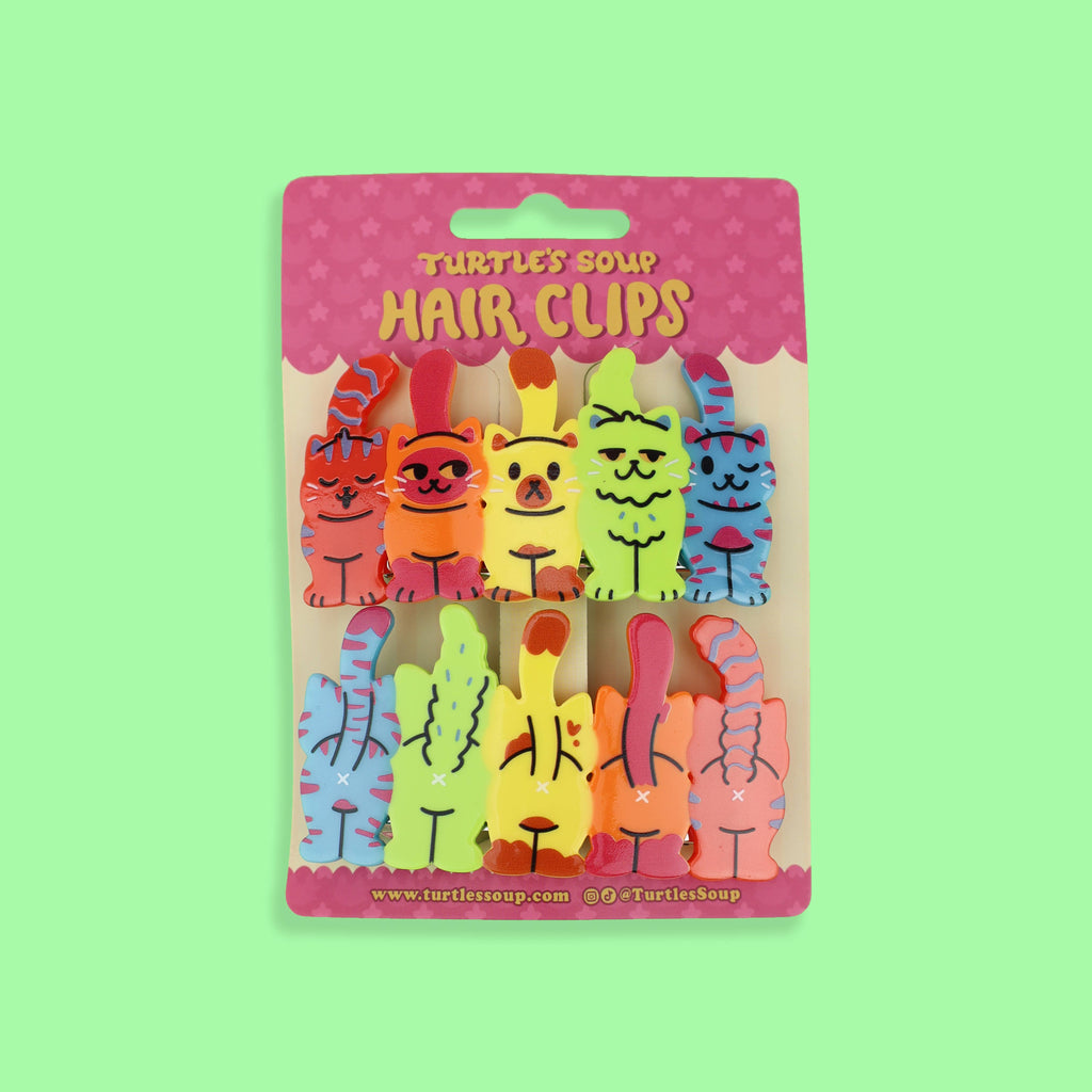 Packaged hair clips with colorful animal designs on a green background