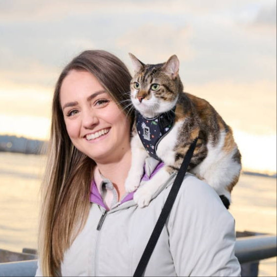 Woman with a cat on her shoulder by a waterfront