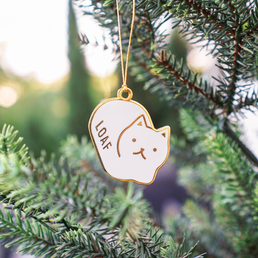 Decorative ornament with a cat design hanging on a Christmas tree.