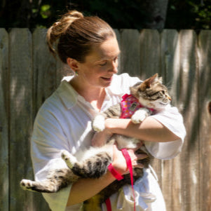 Woman holding a cat against a wooden fence